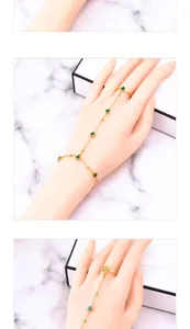 Macro detail of golden hand harness featuring green heart and blue round gemstones