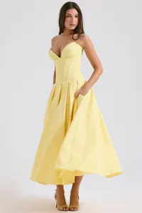 Detail of a yellow bustier maxi dress featuring corset boning and a large pleated skirt