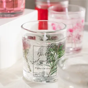 Macro shot of jelly wax scented candle featuring red roses and green leaves in clear glass