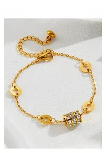 Detail of gold bracelet with Roman numeral rings and cylinder pendant with zircons