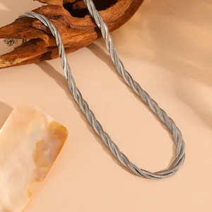Vue détaillée du collier tressé à trois rangs en maille serpent argentée sur bois