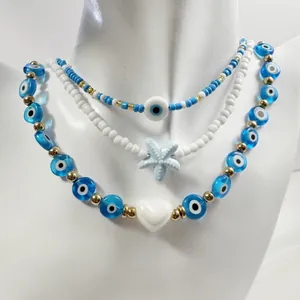 Detail view of triple-layered evil eye beaded necklace with starfish and heart charms