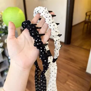 Close-up of black and white polka dot ruffled headband with anti-slip teeth.