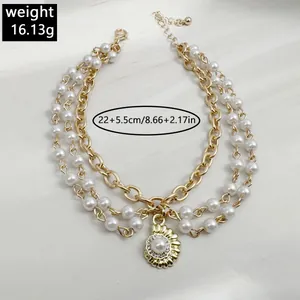 Close-up view of golden three-layer anklet featuring white pearls and a stylish shell pendant