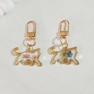 Delicate cat-shaped resin keychain featuring real dried flowers in gold metal frame