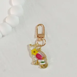 Detailed view of cat-shaped resin keychain with yellow and pink real dried flowers