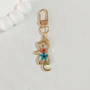 Close-up of cat-shaped resin keychain with embedded dried flowers and golden clasp