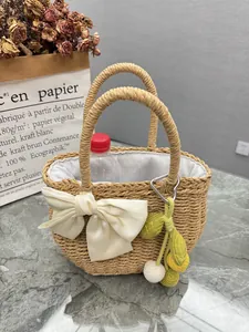 Detail of hand-woven straw holiday handbag with white bow and lemon charm