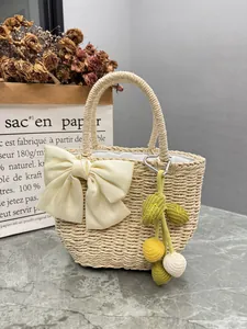 Detailed view of handmade straw bag with cream bow and fruit charm