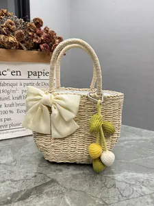 Elegant handmade woven straw handbag featuring a large silk bow and knitted charms.