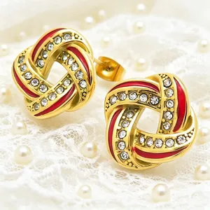 Close-up of gold stainless steel geometric earrings with red enamel and rhinestones.
