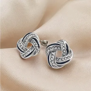 Macro detail of elegant silver knot earrings with sparkling crystals and navy enamel