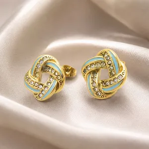 Close-up of gold stainless steel cross earrings with blue enamel and crystals.