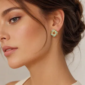 Close-up of elegant gold knot earrings with turquoise enamel and rhinestones on model