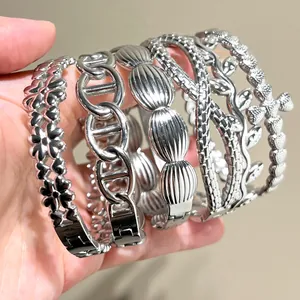 Detailed view of multiple silver stainless steel bracelets with leaf and chain designs