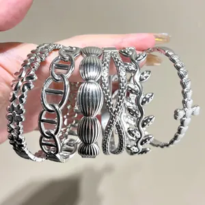 Close-up of multiple silver stainless steel bracelets with flower and leaf patterns