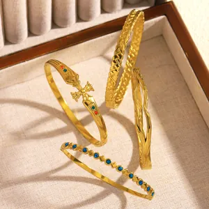 Detailed view of four golden fashion stainless steel bracelets in a jewelry display tray