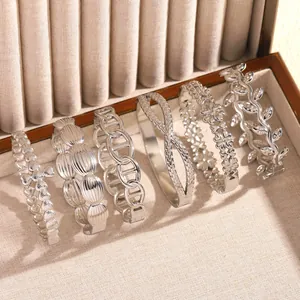 Detailed view of diverse stainless steel bangles with floral and geometric patterns