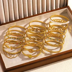 Detail view of various gold stainless steel bangles with floral and geometric patterns