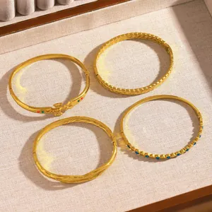 Detailed overhead view of four assorted gold-finish stainless steel bangles in tray