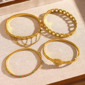 Detailed close-up shot of four gold stainless steel bracelets with flower and chain designs