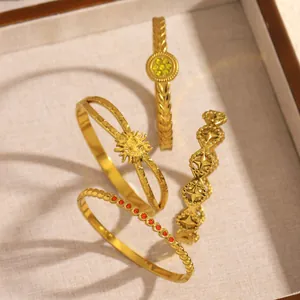 Detailed view of four golden stainless steel bangles with floral and geometric patterns