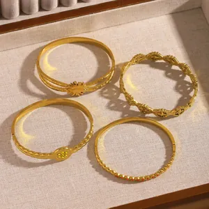 Set of four gold stainless steel bangles with leaf flower and geometric designs