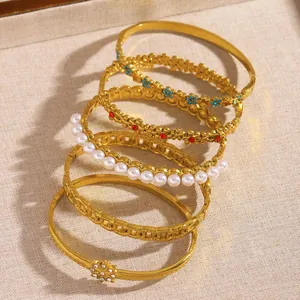 Detailed macro view of various vintage style gold bangles with pearls and flower accents