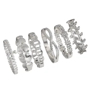 Close-up of six silver stainless steel bangles with floral, leaf and chain motifs