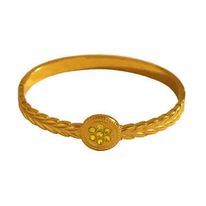 Detailed view of gold stainless steel bangle with leaf patterns and yellow stones