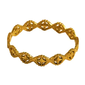 Detailed view of the intricate geometric starburst hollow-out design on a gold bangle