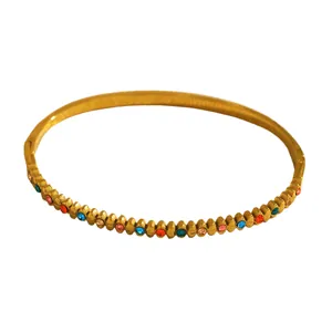 Detailed view of a golden stainless steel bangle featuring colorful rhinestone accents