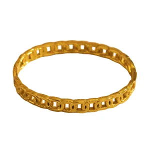 Macro detail of a gold stainless steel chain-link hollow geometric bangle for women
