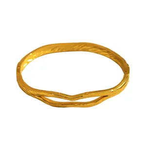 Detail view of gold stainless steel open bangle with organic textured pattern