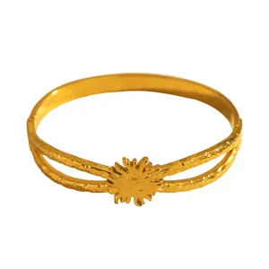 Close-up of gold stainless steel open bracelet with sun flower motif and hammered texture.