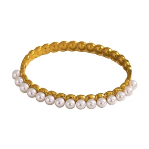 Detailed view of a fashionable gold-plated bangle decorated with white pearls