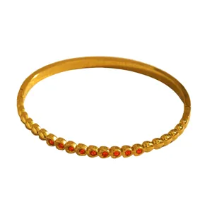 Detailed view of a gold-plated stainless steel bangle featuring red stone heart inlay