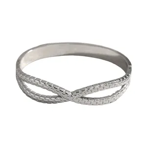 Detailed view of silver stainless steel bangle with textured infinity design pattern