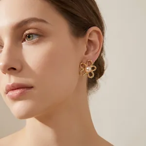 Close-up of gold flower pearl earring worn by model in French vintage style