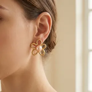 Close-up of French vintage gold flower earring with central pearl on model's ear
