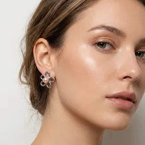 Close-up view of vintage floral stainless steel earrings featuring a pink pearl center