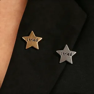 Gold and silver star-shaped metal pins featuring 'i tried' engraving on black jacket lapel