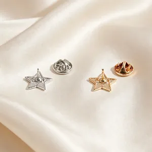 Detailed view of the back of gold and silver star-shaped metal lapel pins on silk.