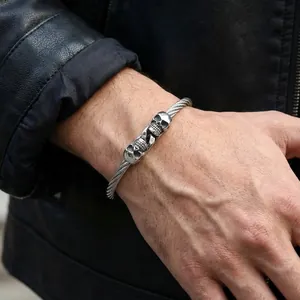Gothic stainless steel wire bracelet featuring dual skull charms for a bold mens look