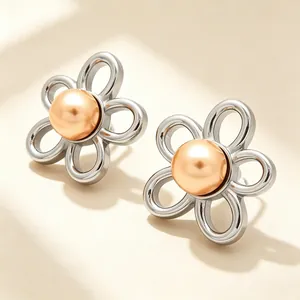 Détail de boucles d'oreilles fleur argentée évidée avec perle dorée élégante