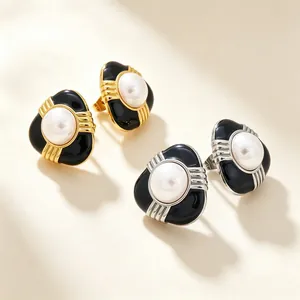 Gros plan sur des boucles d'oreilles émaillées minimalistes avec perles blanches en or et argent.