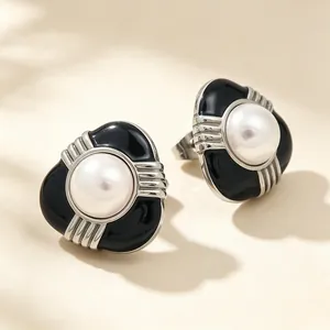 Détail rapproché de boucles d'oreilles en acier inoxydable avec émail noir et perle blanche