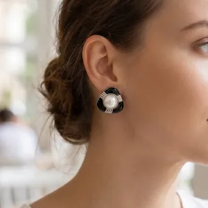 Gros plan d'une boucle d'oreille vintage en émail noir avec perle centrale sur l'oreille