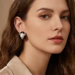 Gros plan de boucles d'oreilles minimalistes en émail noir et perle sur un mannequin