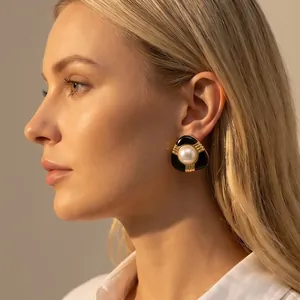 Gros plan élégant d'une boucle d'oreille vintage en émail noir et perle sur mannequin.